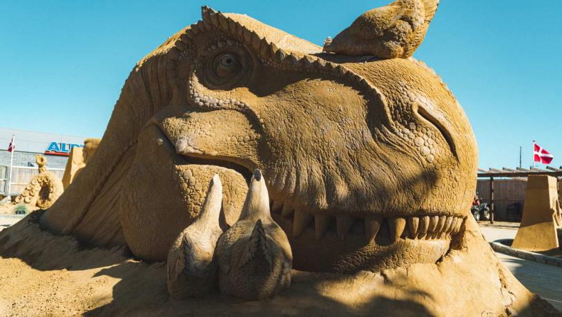  A dinosaur made of sand smiles in Hundested Sand Sculpture Park.