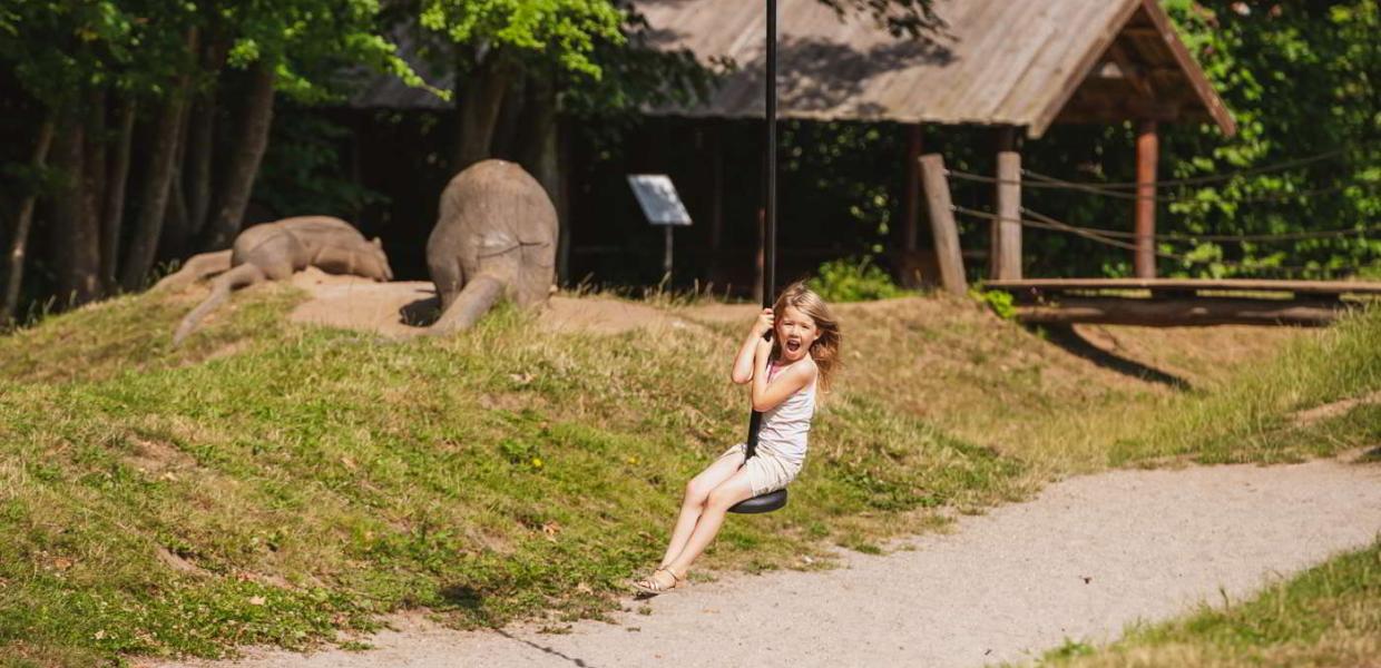 A girl is laughing while flying away on the zipline at the Esrum Abbey's nature playground.