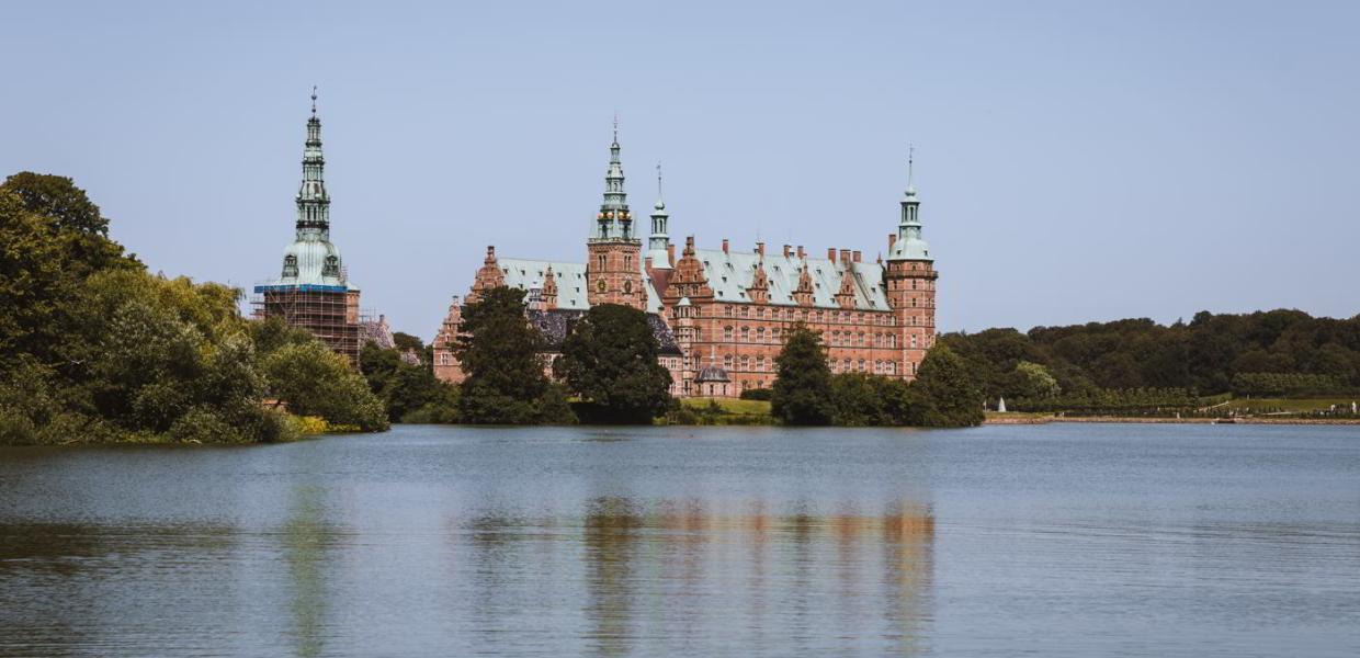 Frederiksborg Castle with the castle lake in front, as seen from the Square in Hillerød on a summer day.