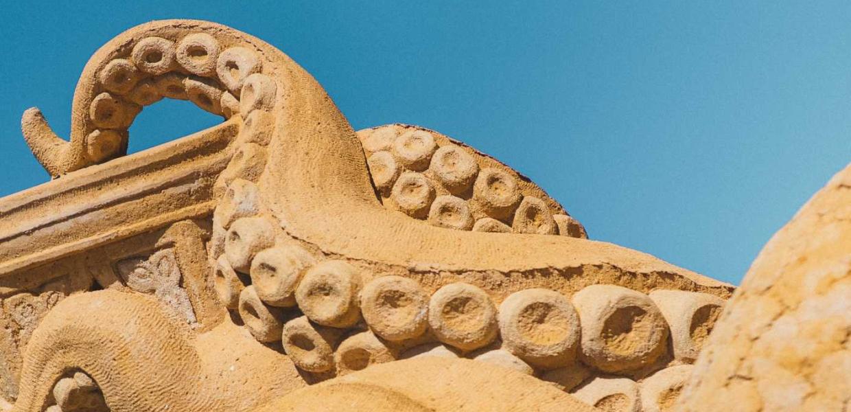 A squid in sand stretches its tentacles towards the sky in Hundested Sand Sculpture Park.